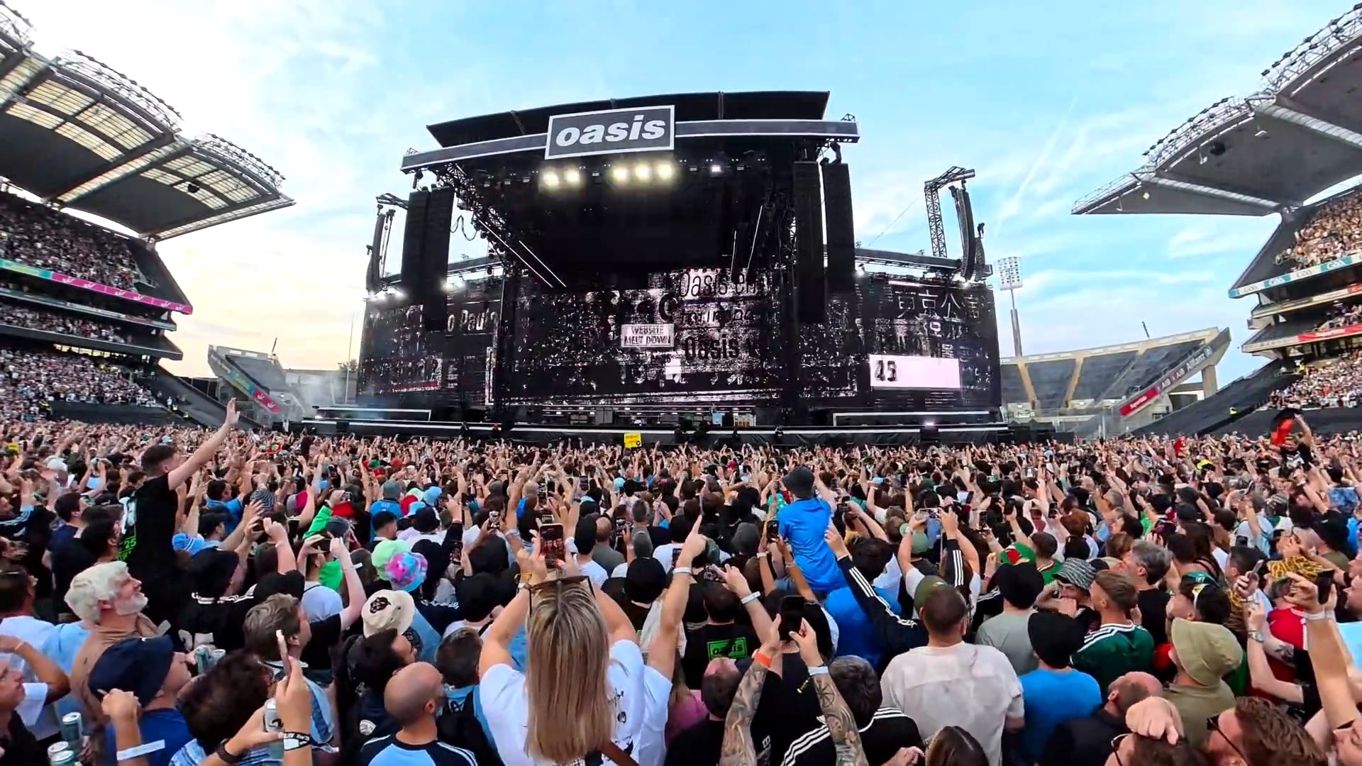 A crowd with hands in the air at an open-air concert