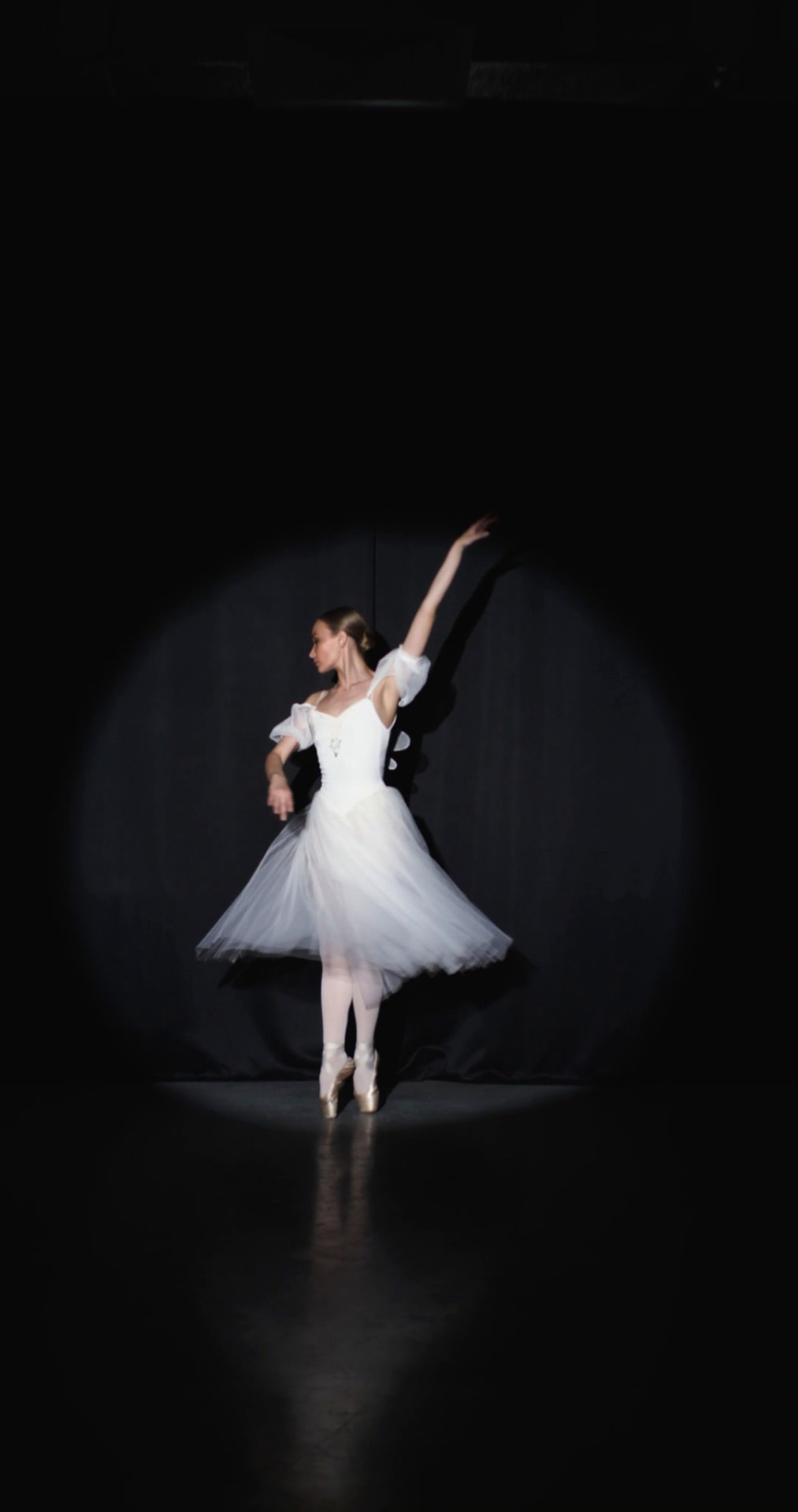 A ballet dancer performing alone in a spotlight on stage
